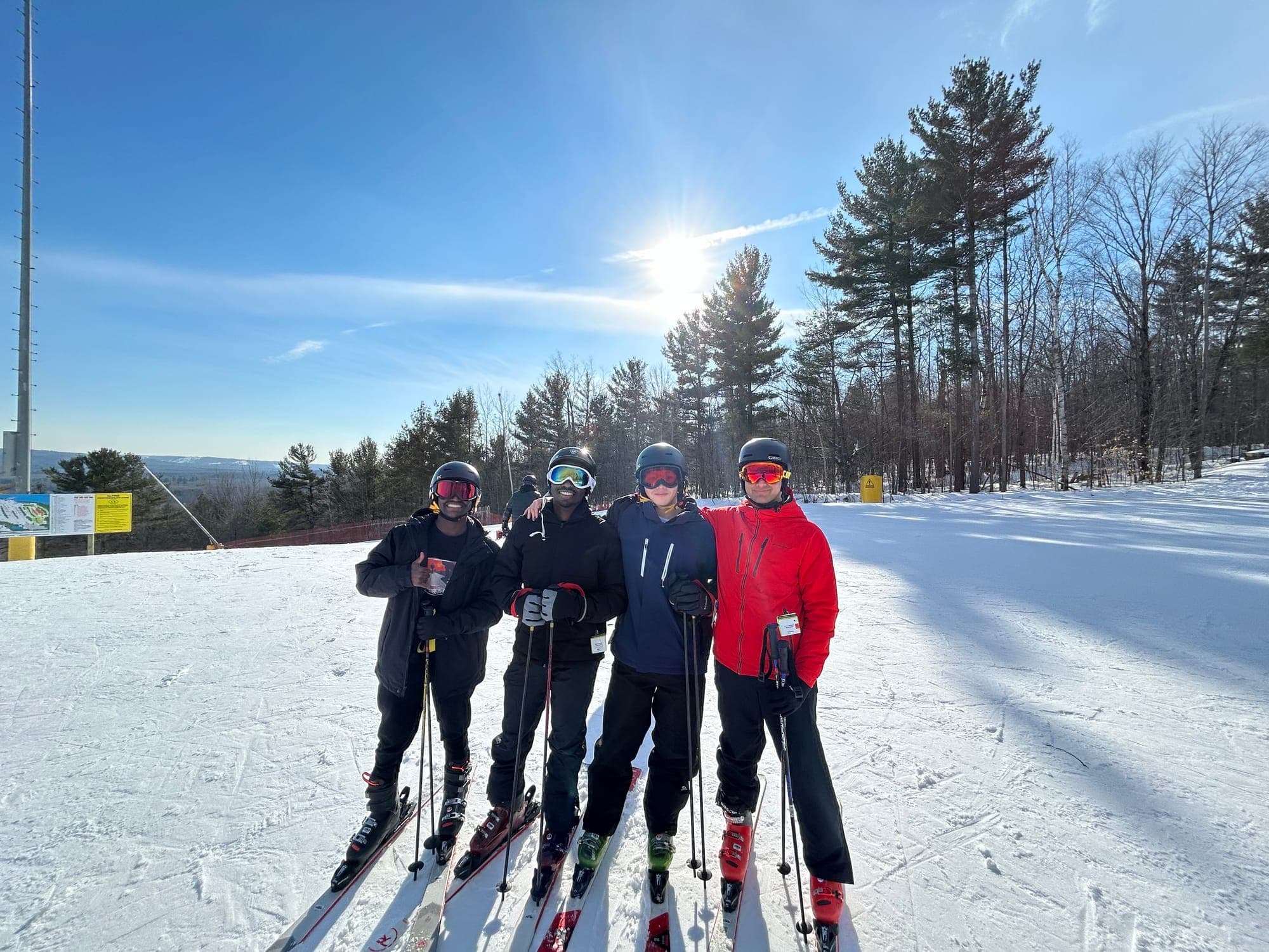 Four friends standing on skis on a sunny day